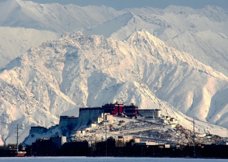 The iconic Potala Palace stands majestically against a serene snowy landscape in winter
