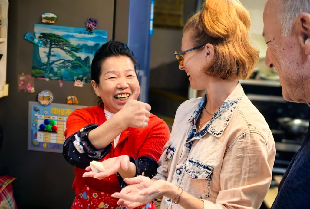 Tourists learn how to make dumplings at a local resident's home