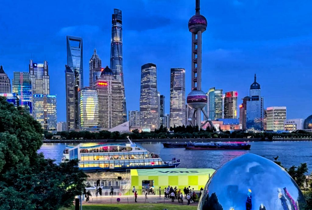 Evening view of Shanghai Lujiazui skyline viewed from riverside park with tourist cruise ship