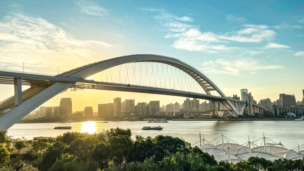 Golden sunset over Shanghai, with Lupu Bridge spanning the Huangpu River.