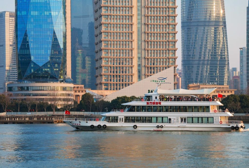 Oriental Pearl cruise ship sailing on Huangpu River, with Lujiazui modern skyscrapers in the background
